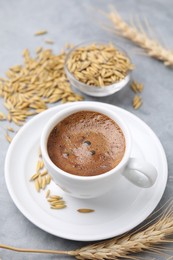 Photo of Cup of barley coffee, grains and spike on gray table, closeup