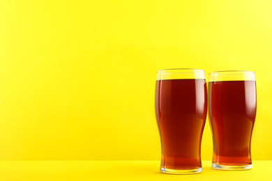Photo of Delicious homemade kvass in glasses on yellow background. Space for text