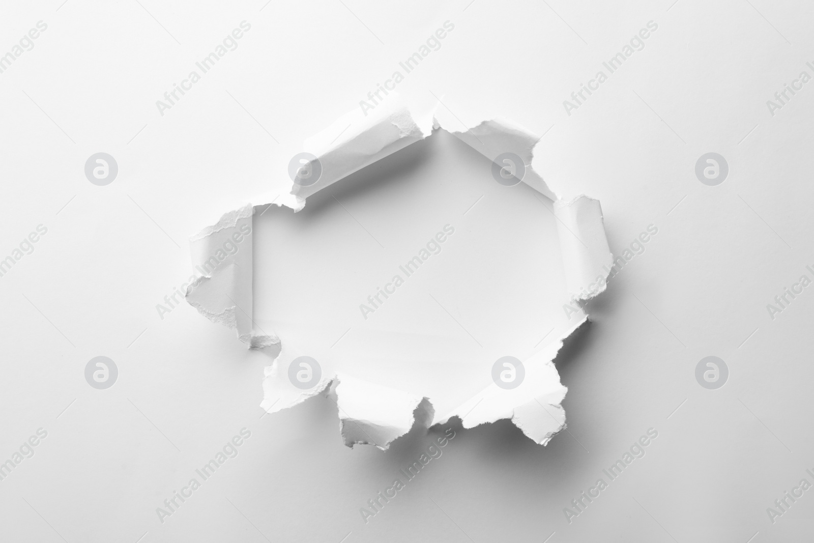 Photo of Hole in white paper on light background