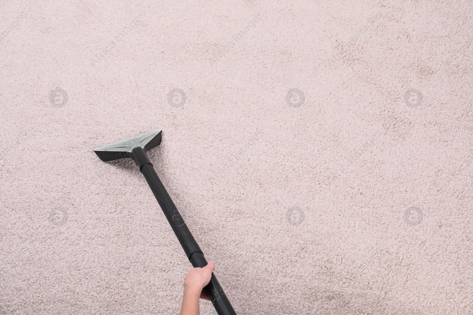 Photo of Woman cleaning carpet with vacuum cleaner, top view. Space for text