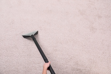 Photo of Woman cleaning carpet with vacuum cleaner, top view. Space for text