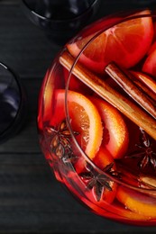 Photo of Glass bowl of delicious aromatic punch drink on black wooden table, top view