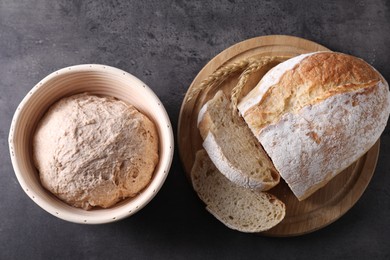 Photo of Fresh sourdough in proofing basket and bread on grey table, top view