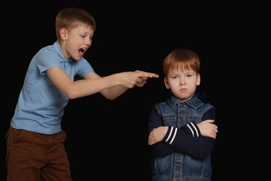 Photo of Boy laughing and pointing at upset kid on black background. Children's bullying