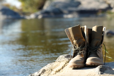 Boots on sand near pond. Space for text