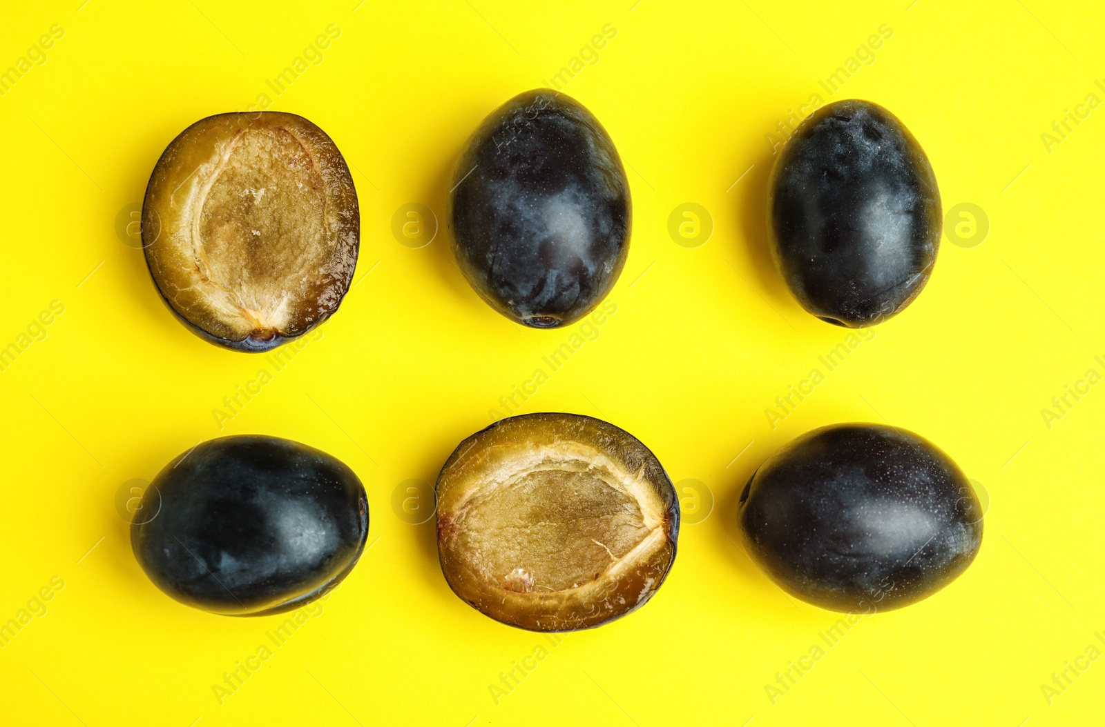 Photo of Delicious ripe plums on yellow background, flat lay