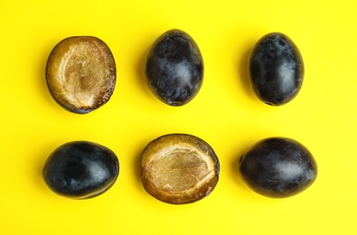 Delicious ripe plums on yellow background, flat lay