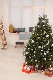 Beautiful Christmas tree and stylish furniture in cozy room. Interior design