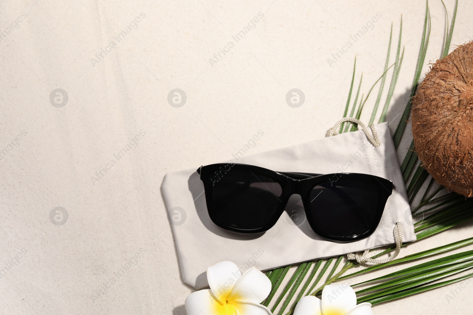 Photo of Flat lay composition with stylish sunglasses and cloth bag on sand. Space for text