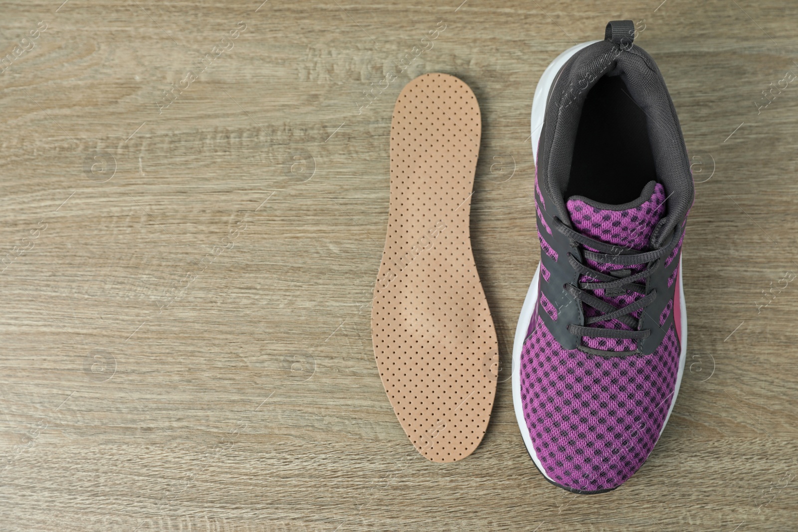 Photo of Orthopedic insole near shoe on floor, flat lay. Space for text