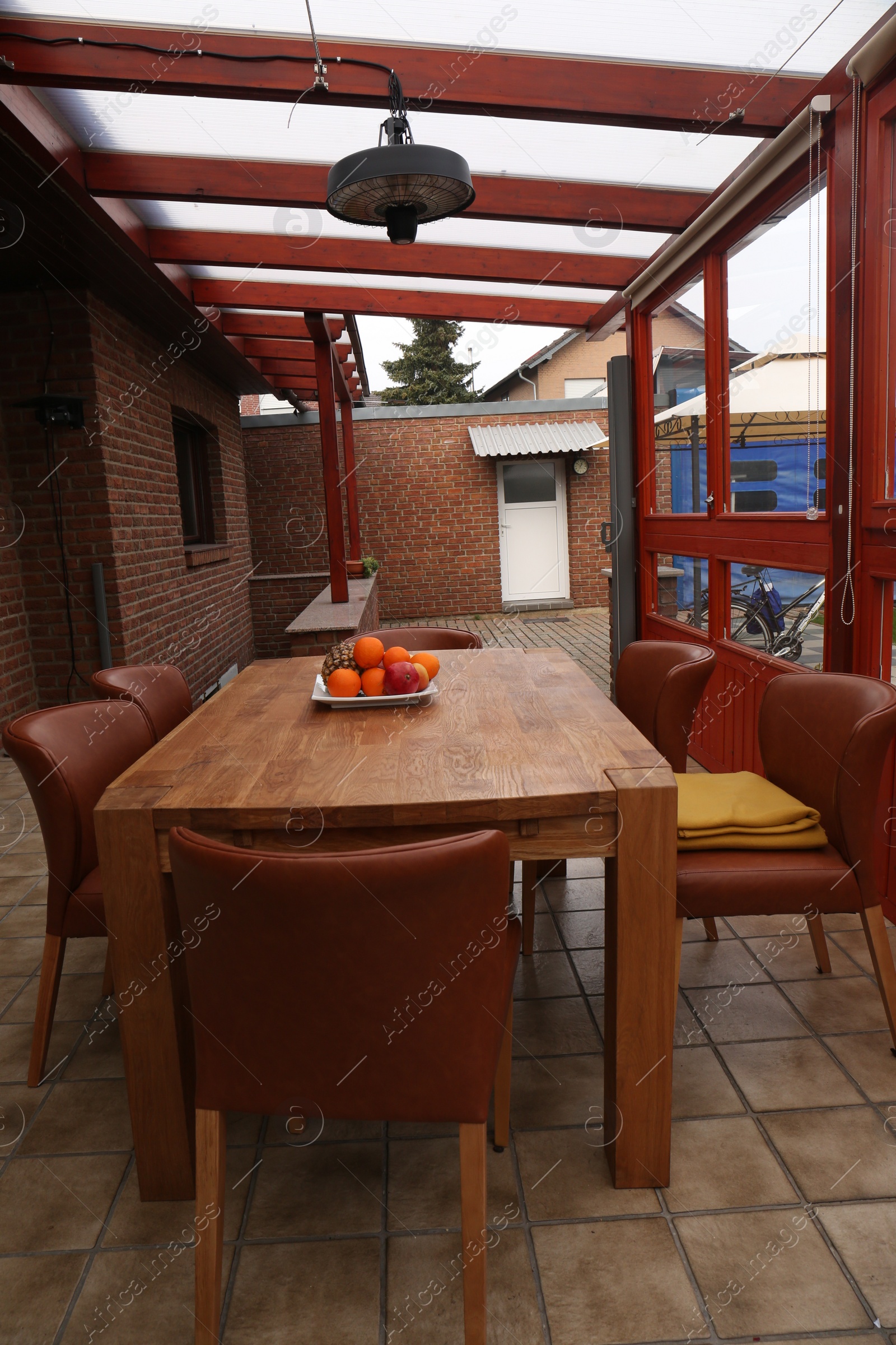 Photo of Wooden table with fruits and stylish chairs on terrace