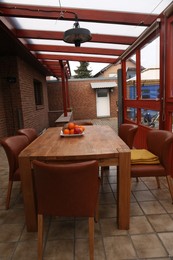 Wooden table with fruits and stylish chairs on terrace