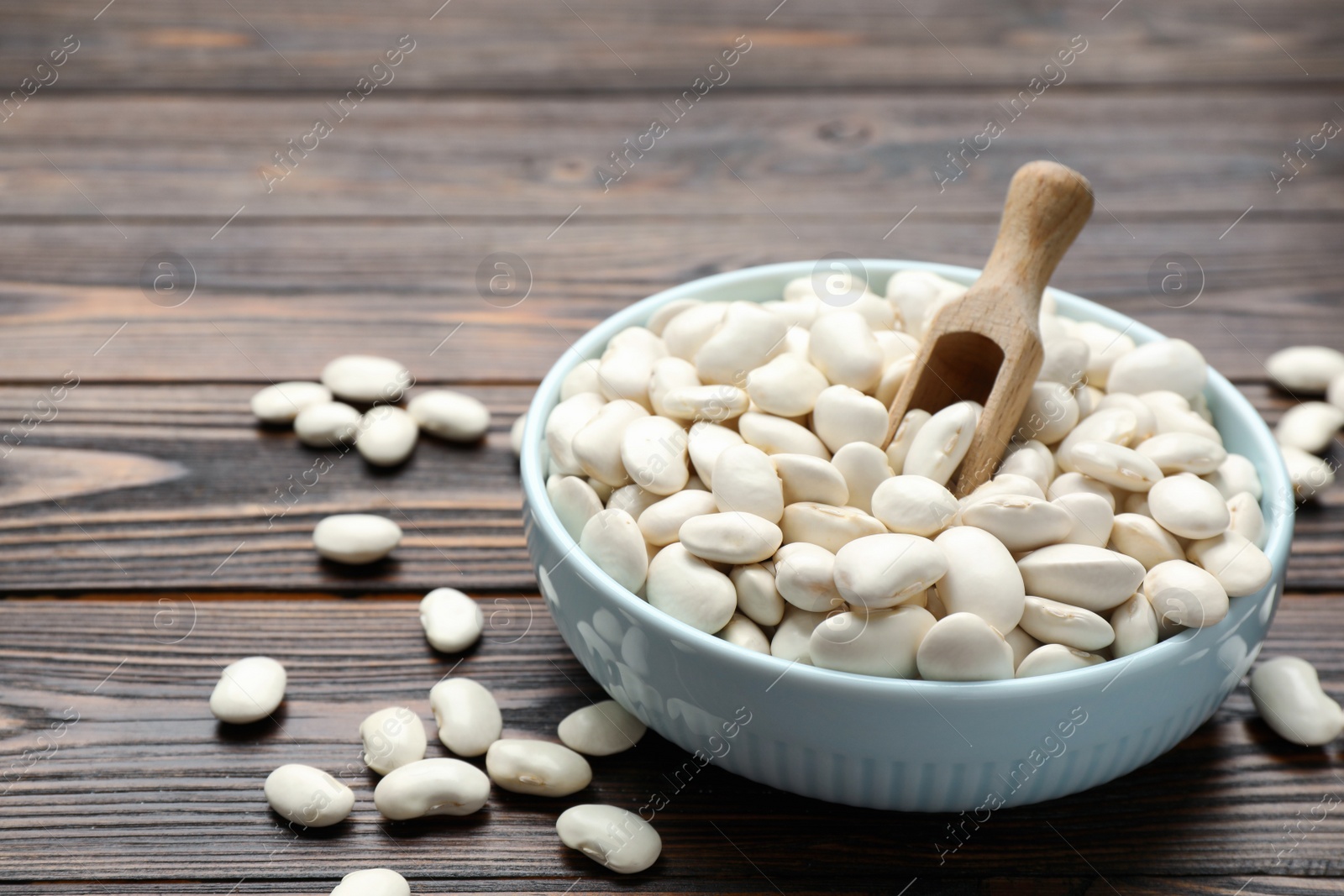 Photo of Raw white beans, bowl and scoop on wooden table, closeup. Space for text