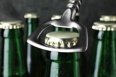 Opening bottle of tasty cold beer on grey background, closeup