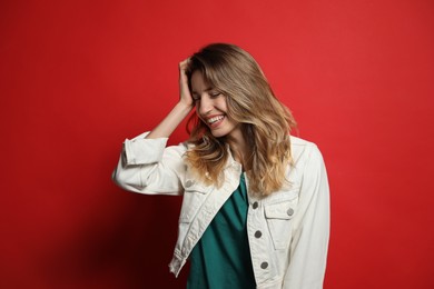 Cheerful young woman laughing on red background