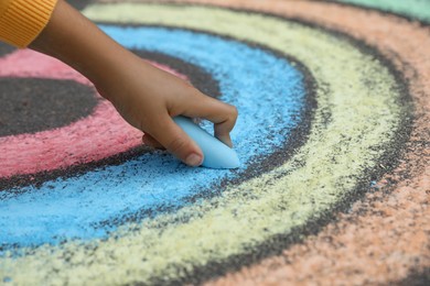 Photo of Child drawing rainbow with chalk on asphalt, closeup
