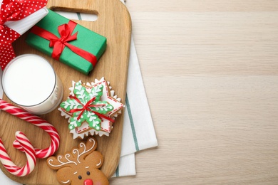 Decorated Christmas cookies and glass of milk on wooden table, top view. Space for text