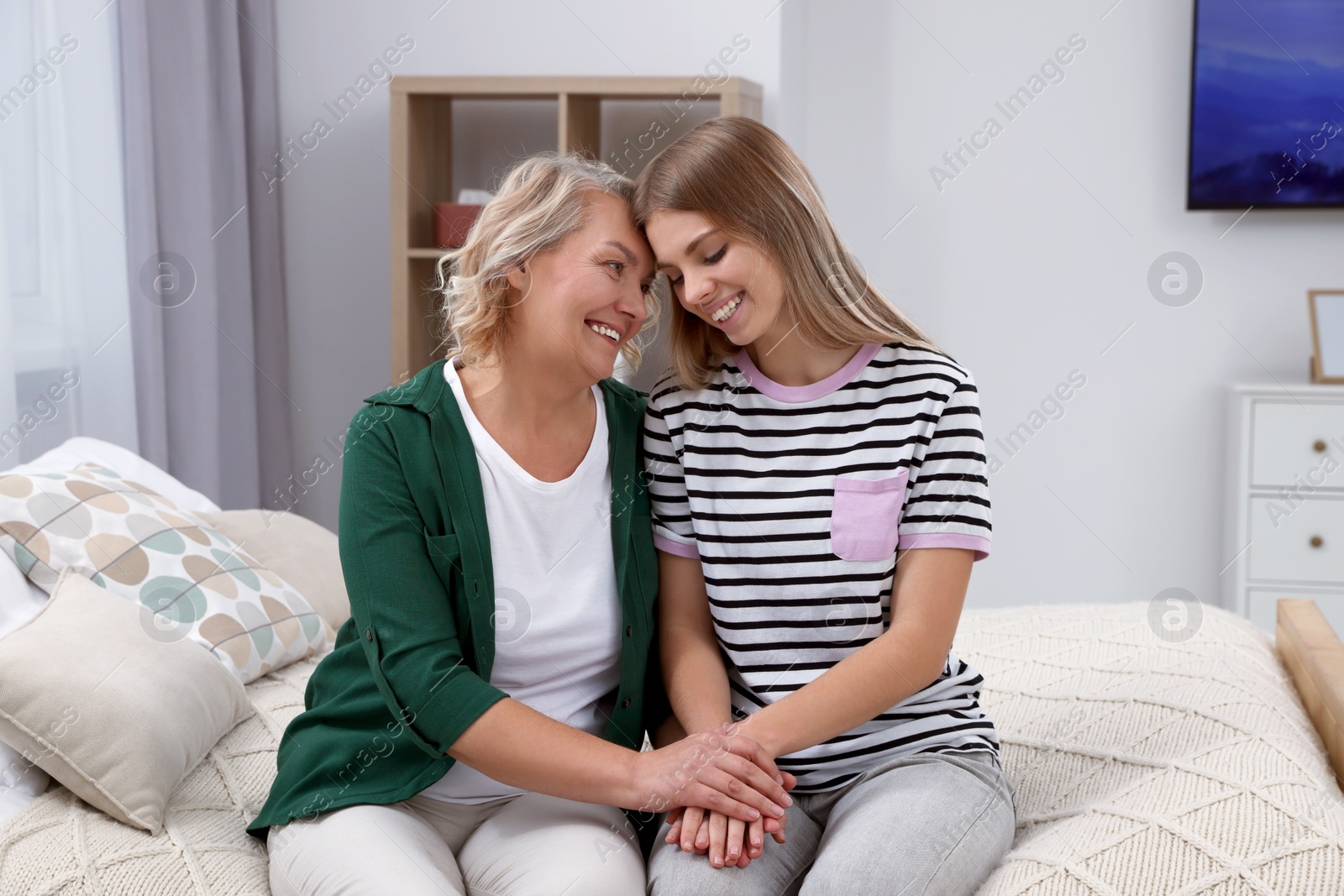 Photo of Young woman with her mom on bed at home. Happy Mother's Day