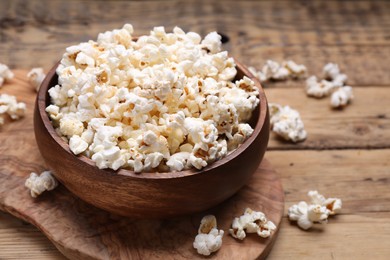 Bowl of tasty popcorn on wooden table, closeup. Space for text