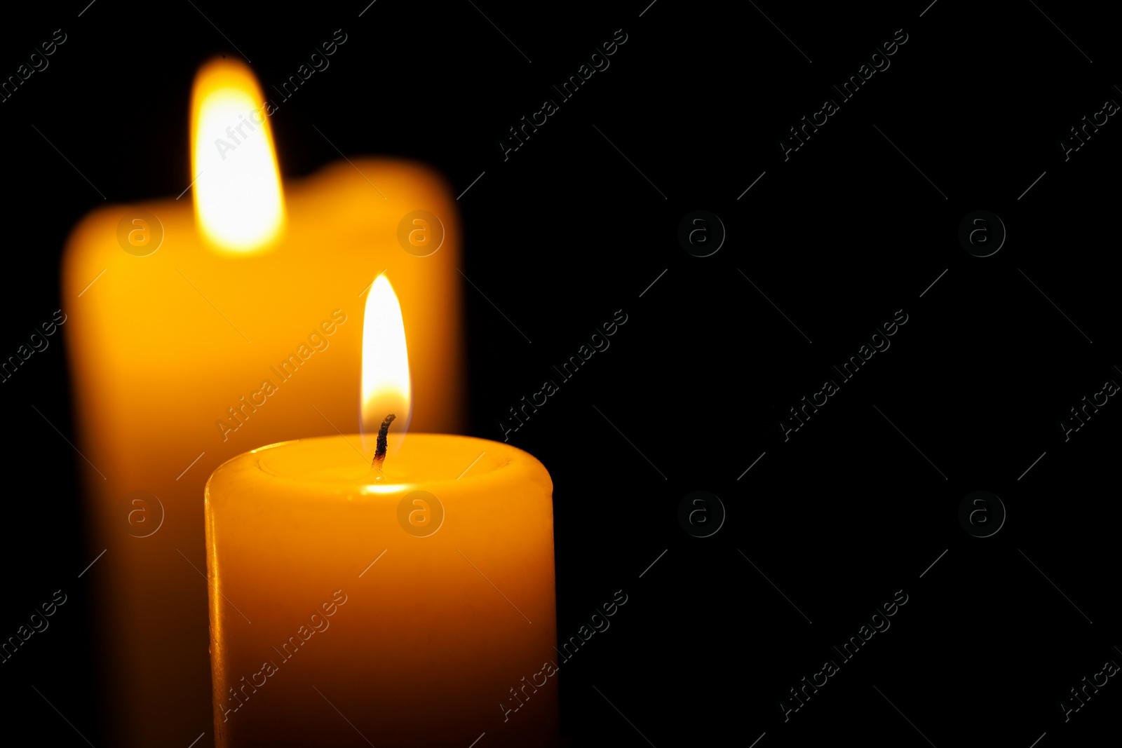 Photo of Burning candles on black background, closeup. Space for text