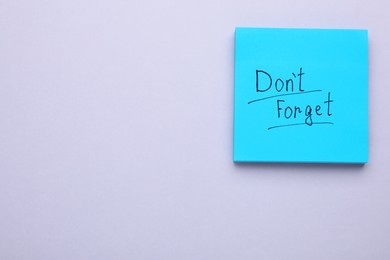 Photo of Paper note with phrase Don't Forget on light grey background, top view. Space for text