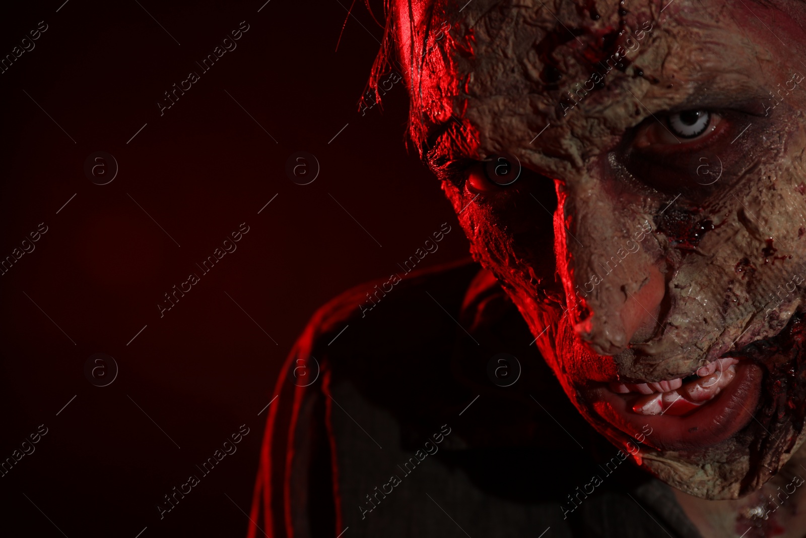 Photo of Scary zombie on dark background, closeup with space for text. Halloween monster