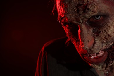 Photo of Scary zombie on dark background, closeup with space for text. Halloween monster