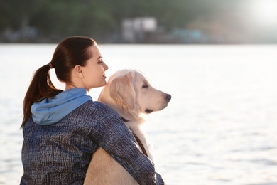 Photo of Young woman with her dog together near river. Pet care