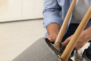 Photo of Man with hex key assembling armchair indoors, closeup. Space for text