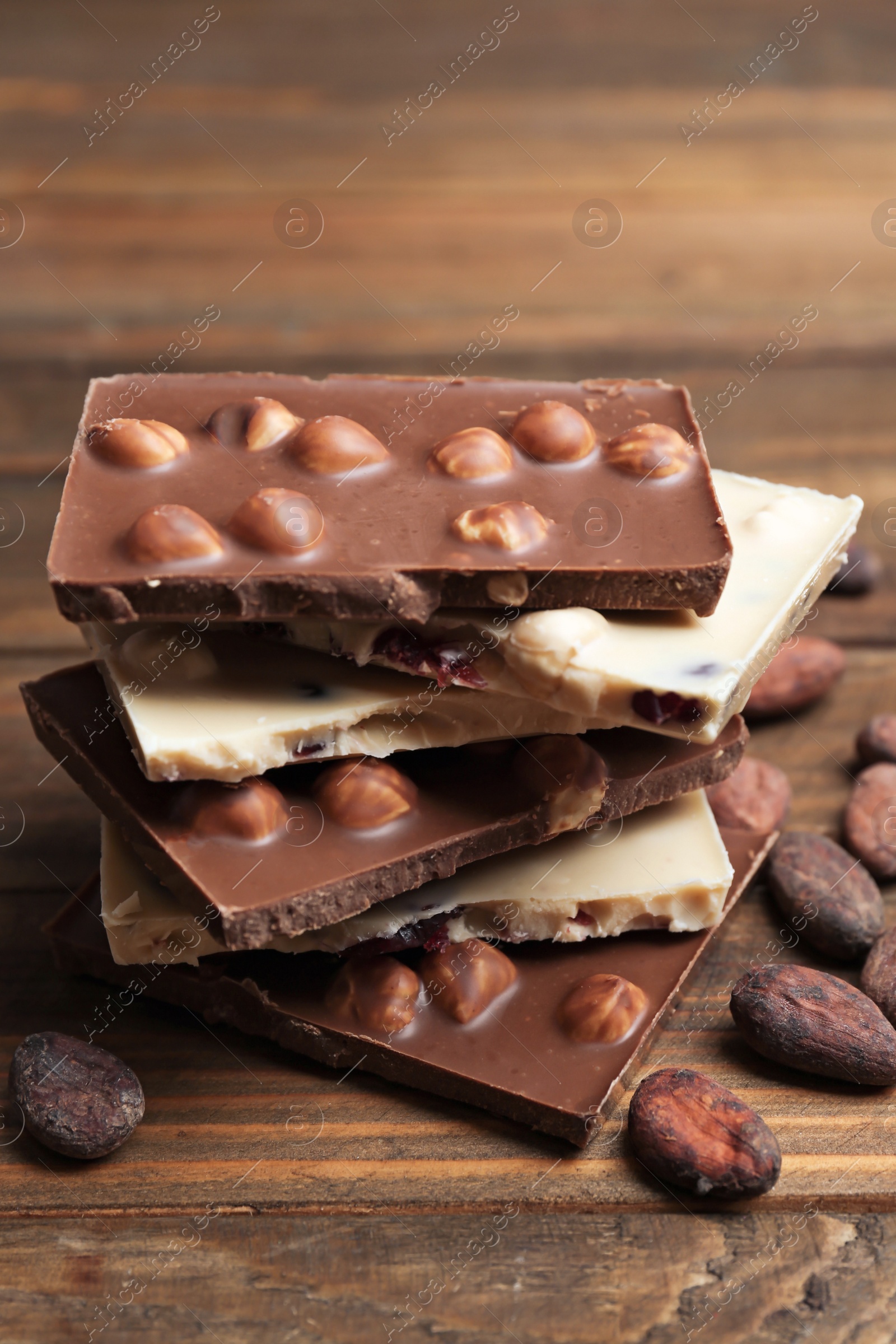 Photo of Yummy chocolate pieces with hazelnuts on wooden table