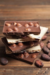 Photo of Yummy chocolate pieces with hazelnuts on wooden table