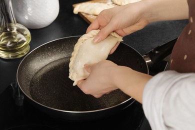 Photo of Woman putting chebureki in frying pan, closeup
