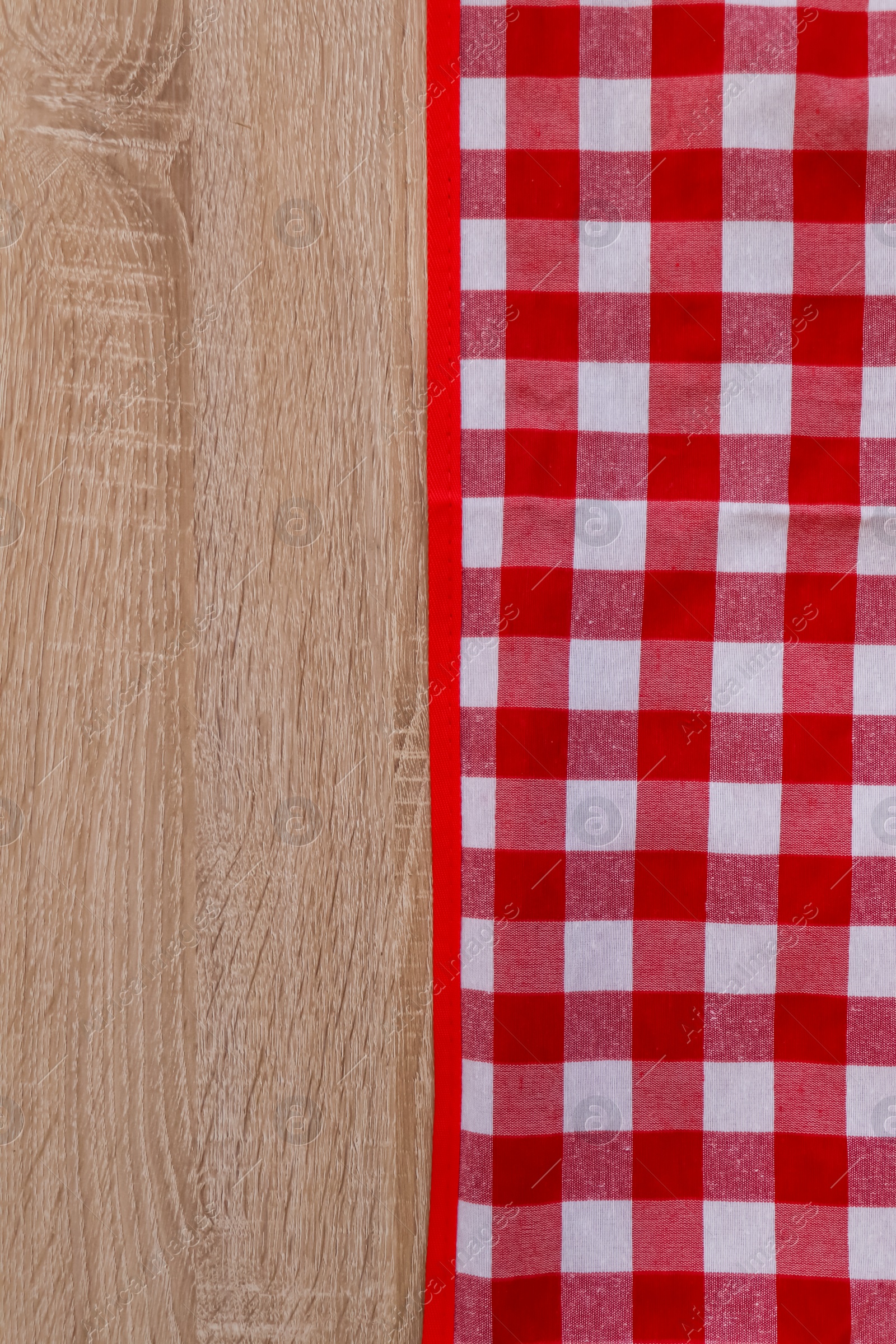 Photo of Checkered picnic cloth on wooden table, top view. Space for text