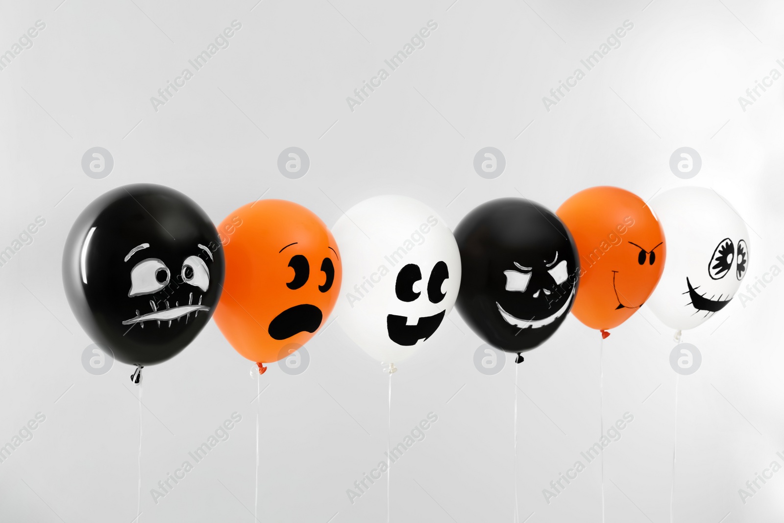 Photo of Spooky balloons for Halloween party on light grey background