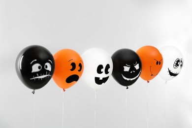 Photo of Spooky balloons for Halloween party on light grey background