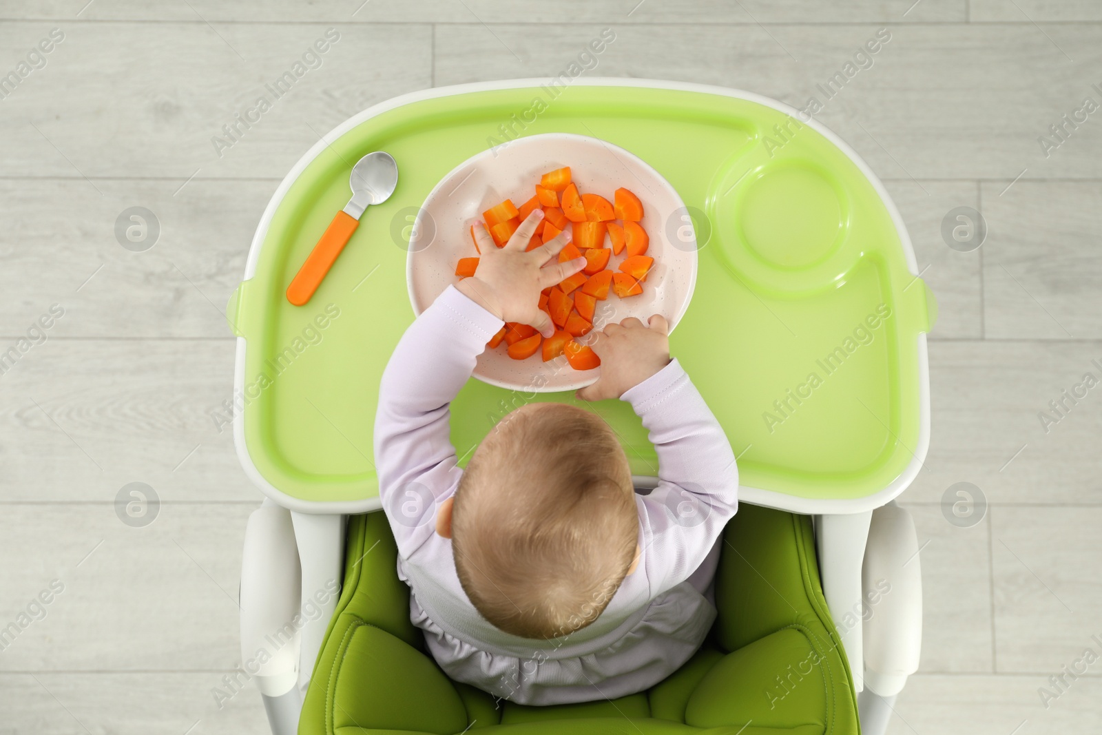 Photo of Cute little baby eating carrot, top view