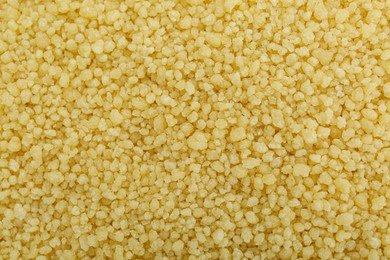 Photo of Raw couscous grains as background, top view