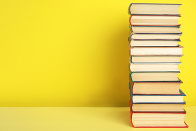 Stack of hardcover books on yellow background. Space for text