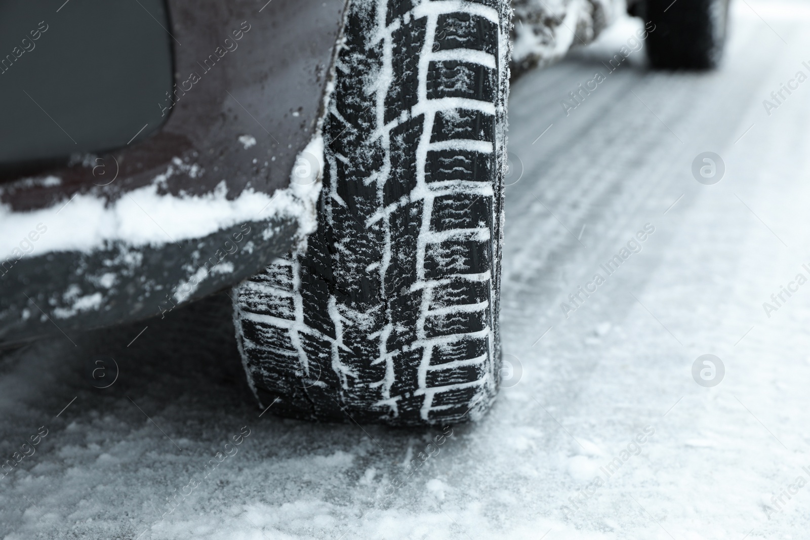 Photo of Modern car with winter tires on snowy road, closeup