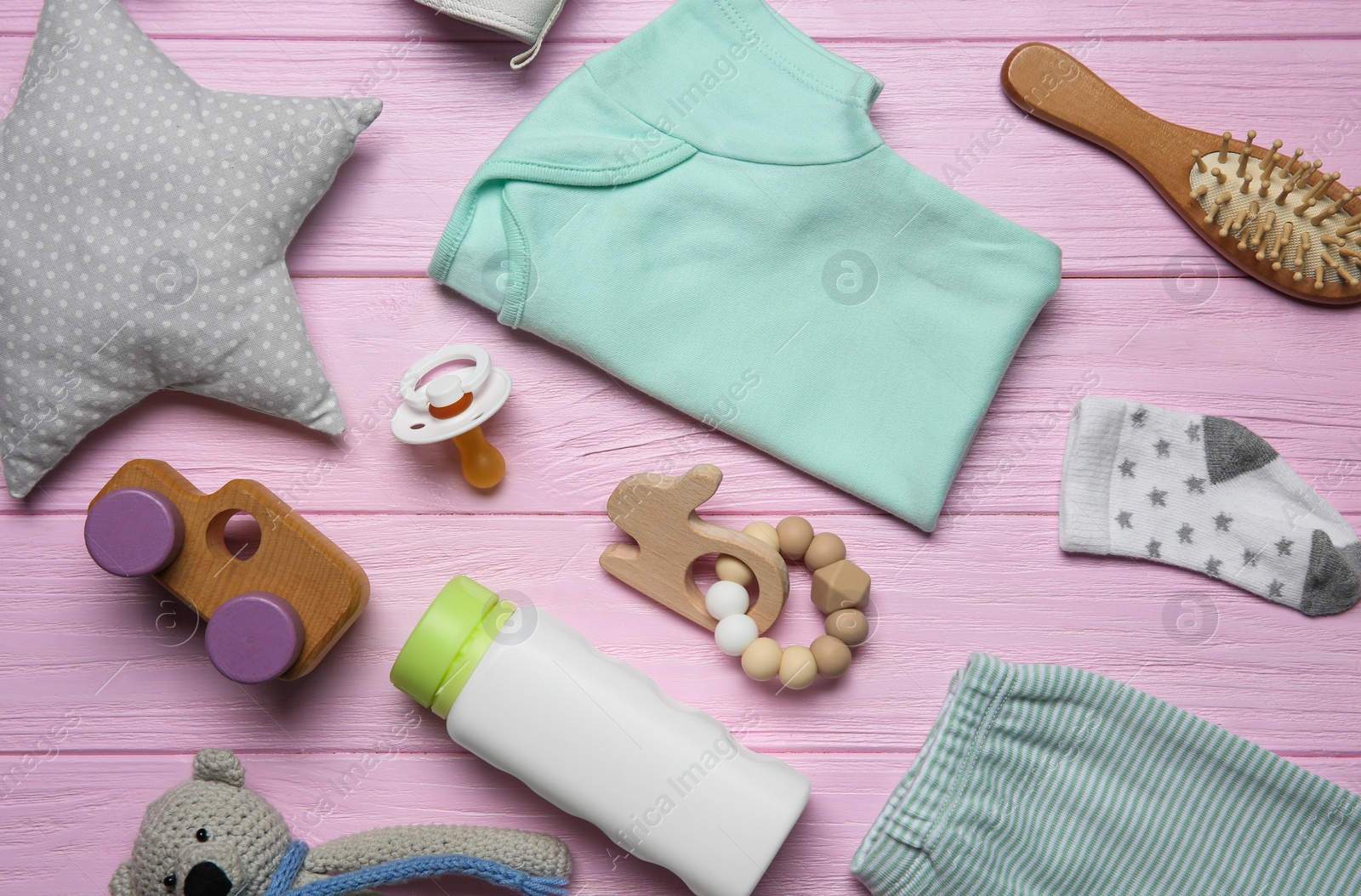 Photo of Baby clothes and accessories on pink wooden background, flat lay