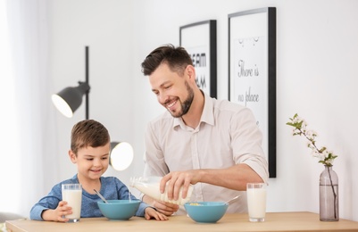 Photo of Father and son having breakfast with milk at table