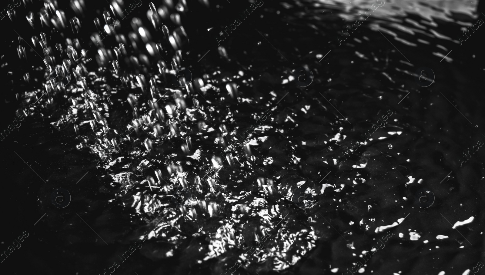 Photo of Heavy rain falling down on ground against dark background, closeup