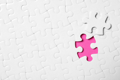 Photo of Blank white puzzle with separated piece on pink background, top view. Space for text