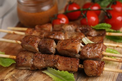 Photo of Tasty cooked marinated meat served with sauce and tomatoes on table, closeup