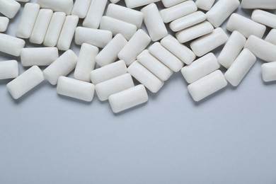 Photo of Tasty white chewing gums on light grey background, flat lay. Space for text