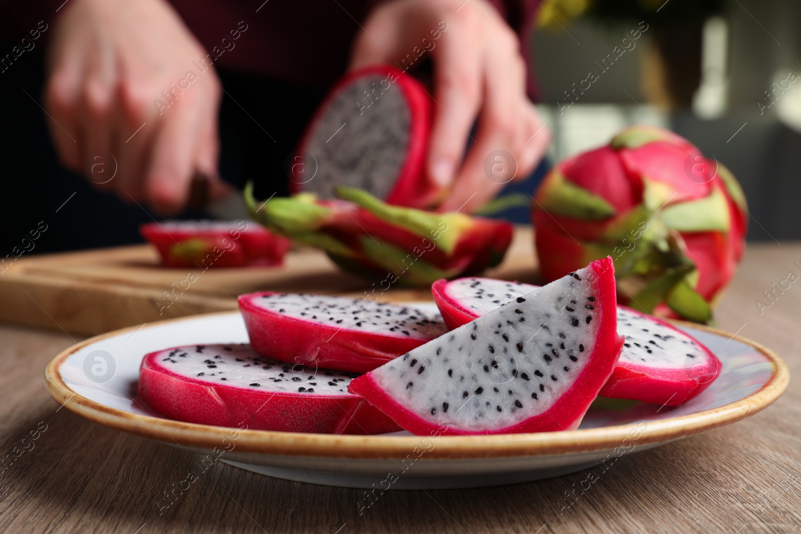 Photo of Plate with delicious cut white pitahaya fruit on wooden table indoors, closeup