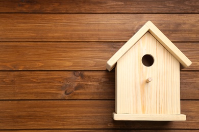 Photo of Beautiful bird house on wooden background, space for text
