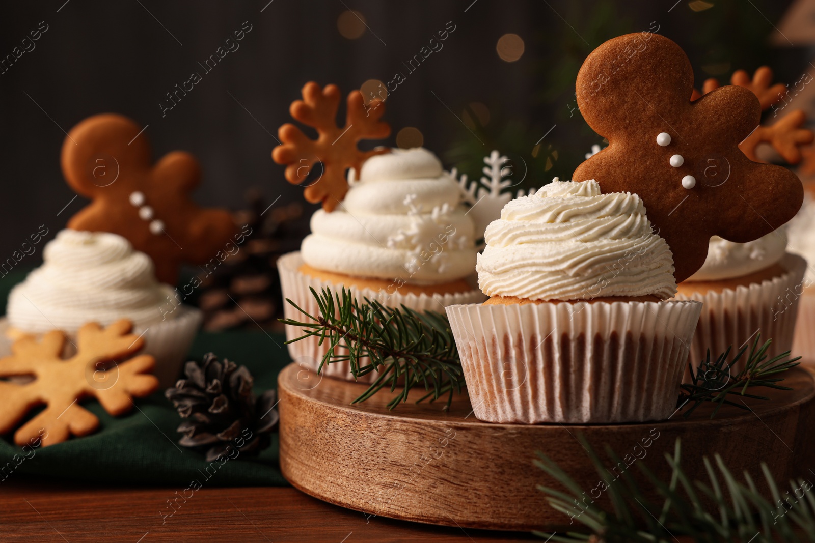 Photo of Different beautiful Christmas cupcakes and fir branches on wooden table. Space for text