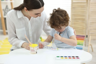 Mother and her little son painting with watercolor at home