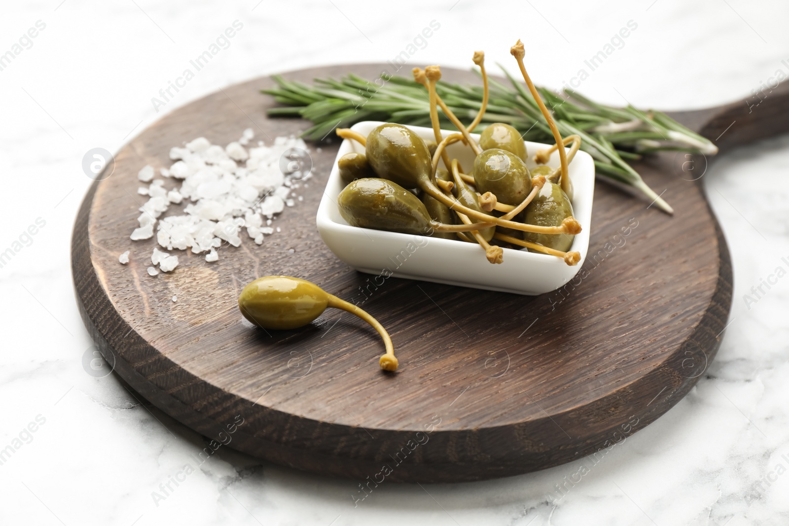 Photo of Delicious pickled capers, salt and rosemary twigs on white marble table